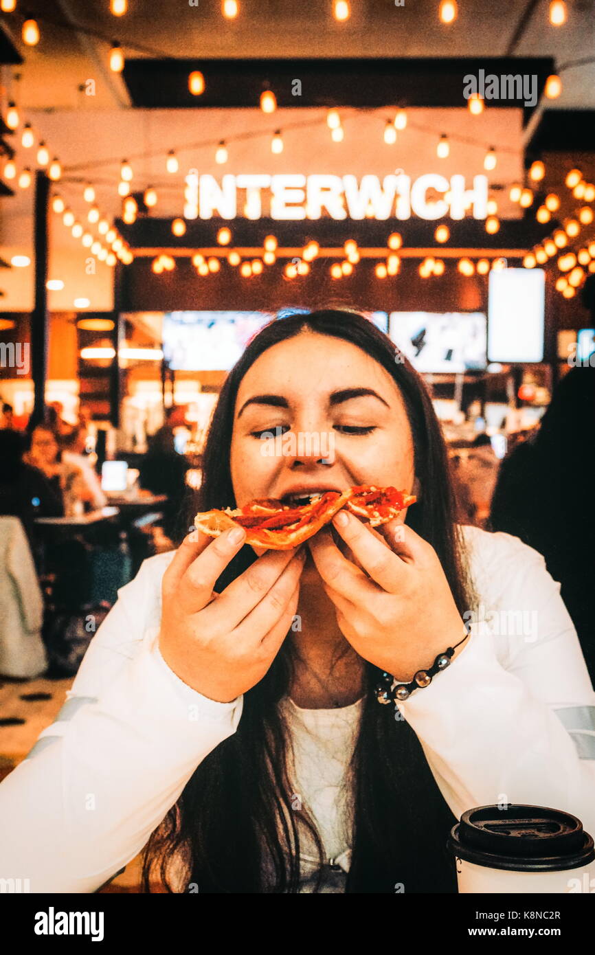 New York, USA -  30 September, 2016: Young Woman eating Pizza at LaGuardia Airport while waiting for her flight. Stock Photo