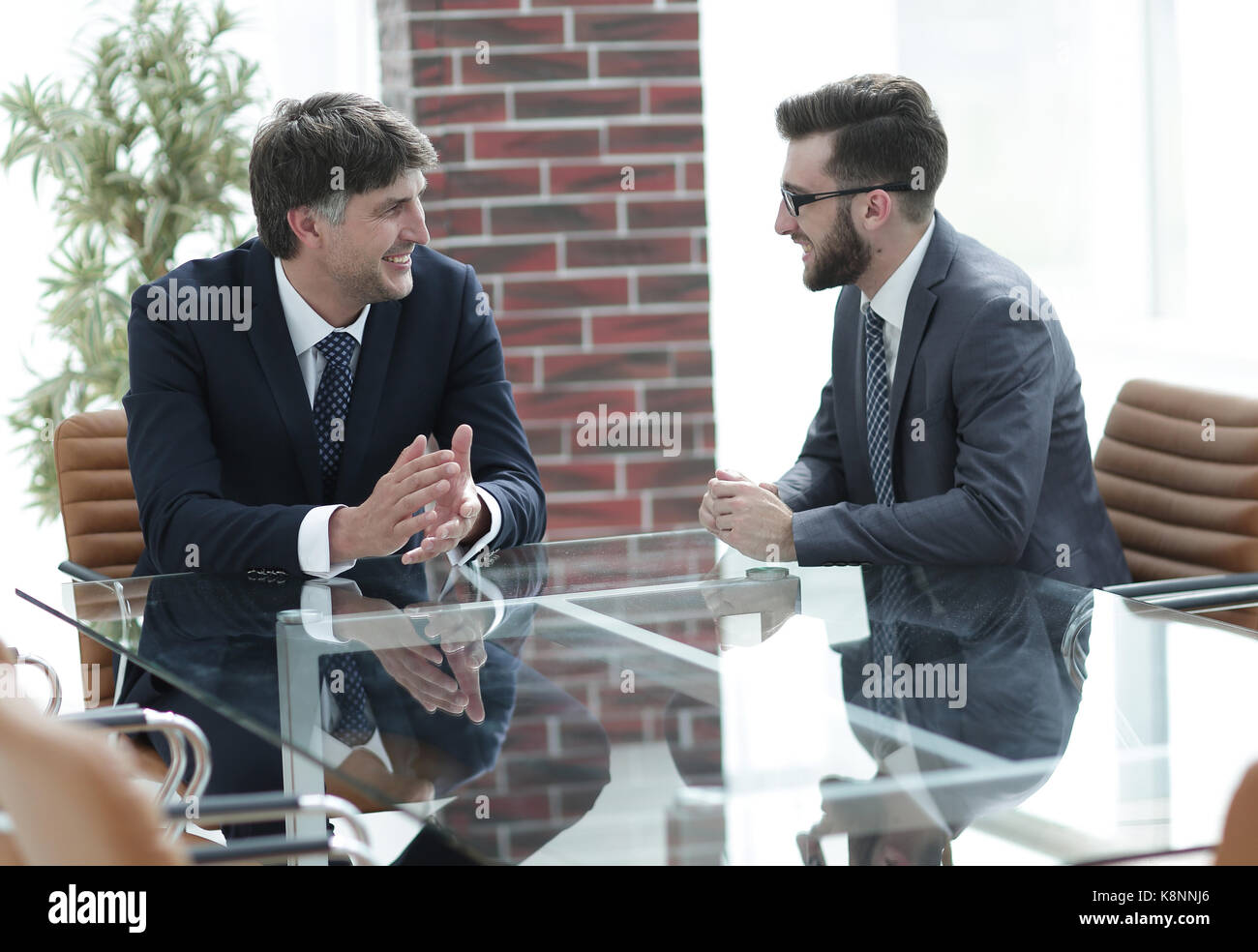 Two businessmen discussing tasks sitting at office table Stock Photo ...
