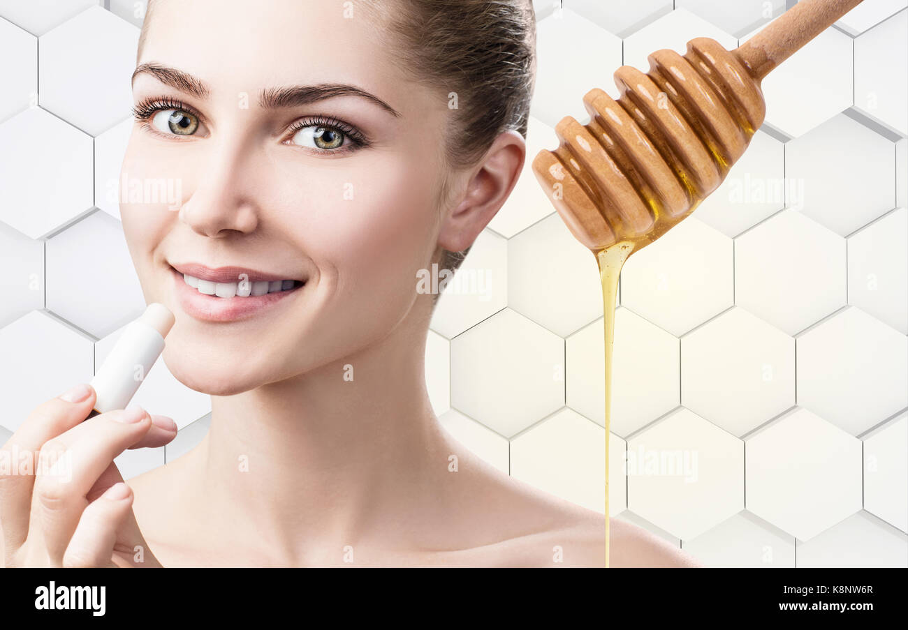 Young woman putting lipbalm with honey on lips Stock Photo Alamy
