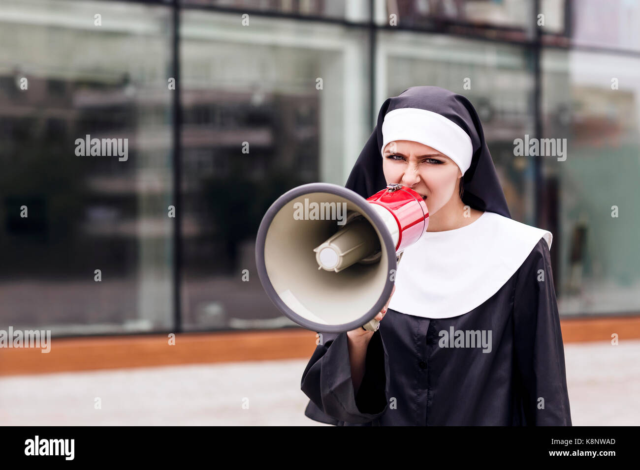 Surprised nun speak to megaphone outdoors. Stock Photo