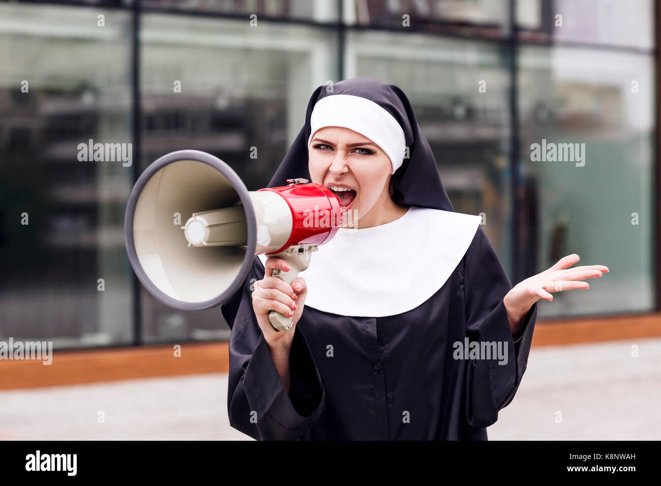 Surprised nun speak to megaphone outdoors. Stock Photo