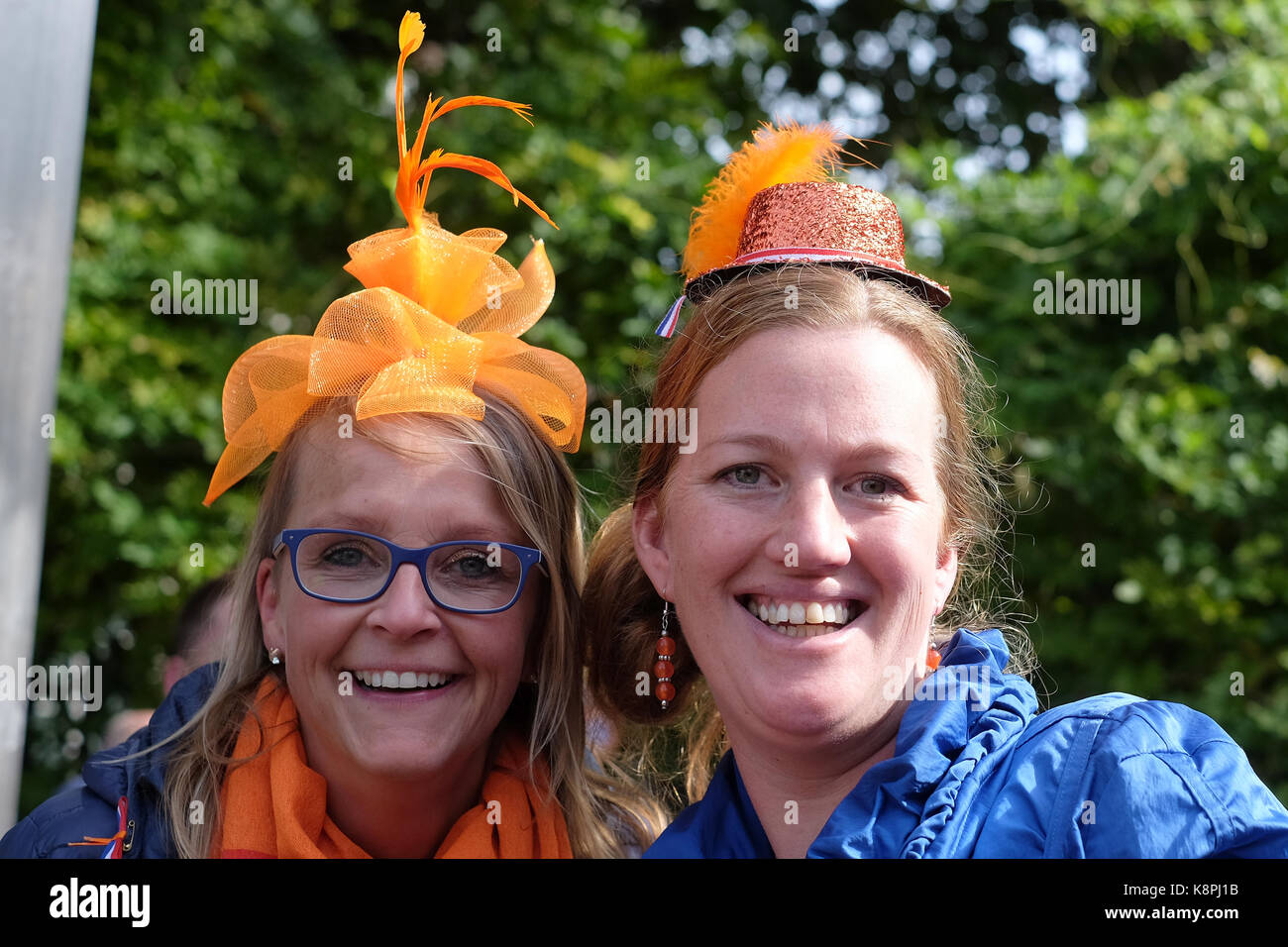 Dutch women wearing orange hats smile after a balcony appearance of the