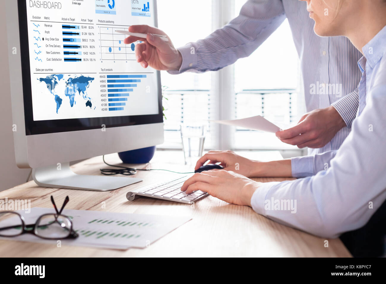 Team of financial people discussing a business analytics (BA) or intelligence (BI) dashboard on the computer screen showing sales and operations data  Stock Photo