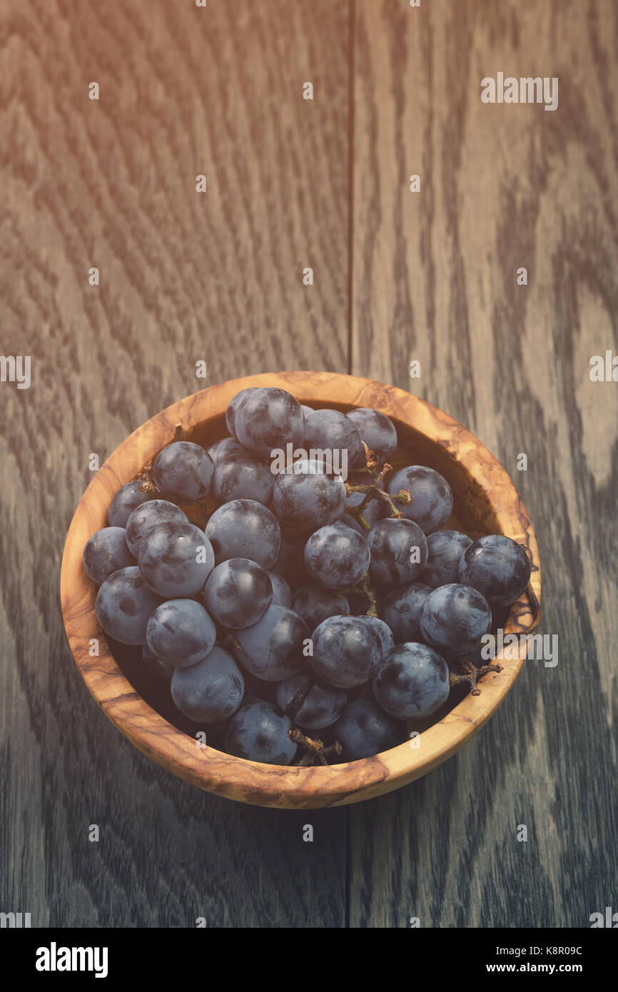 ripe isabella grapes in wood bowl on table Stock Photo