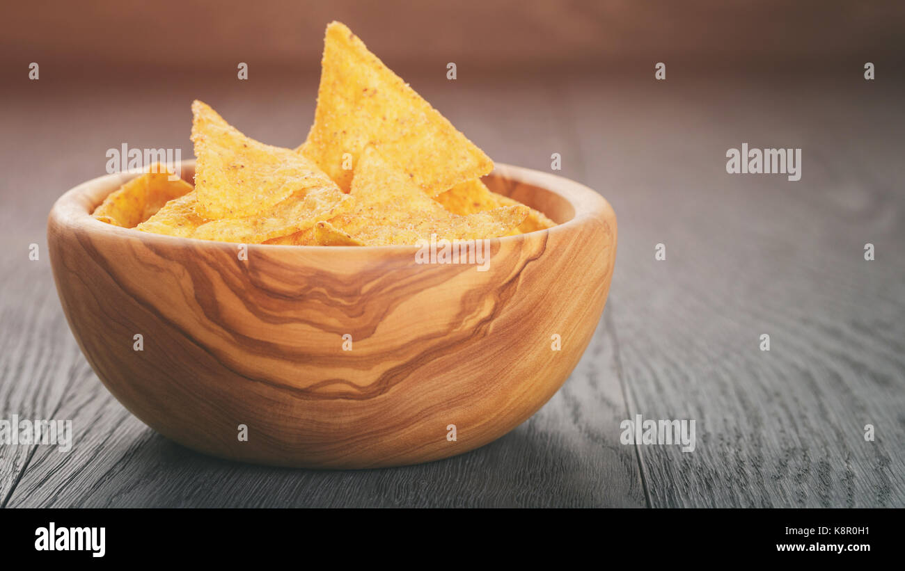 tortilla chips in olive wood bowl on wooden table Stock Photo