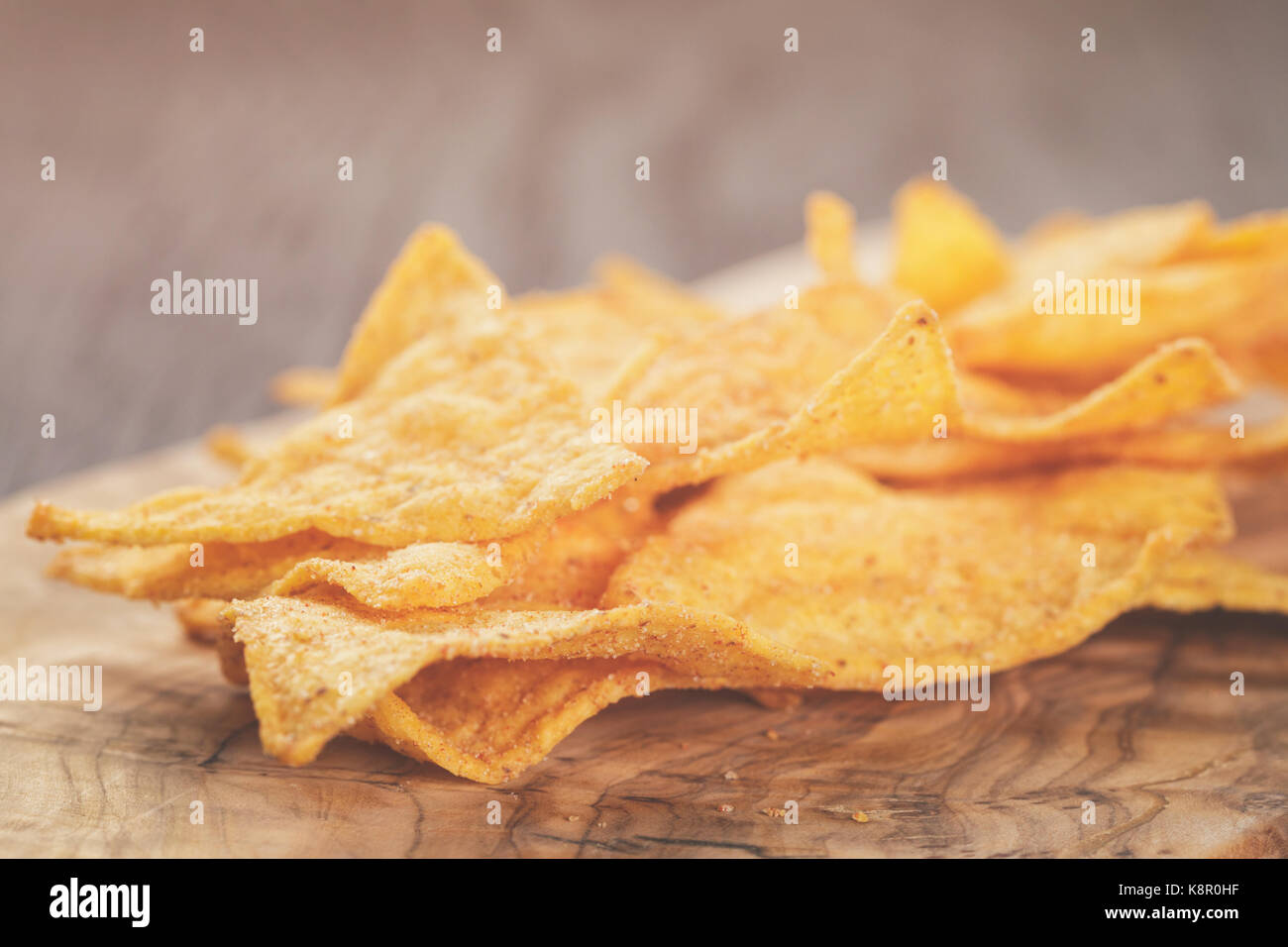heap of tortilla chips on olive board on wooden table Stock Photo