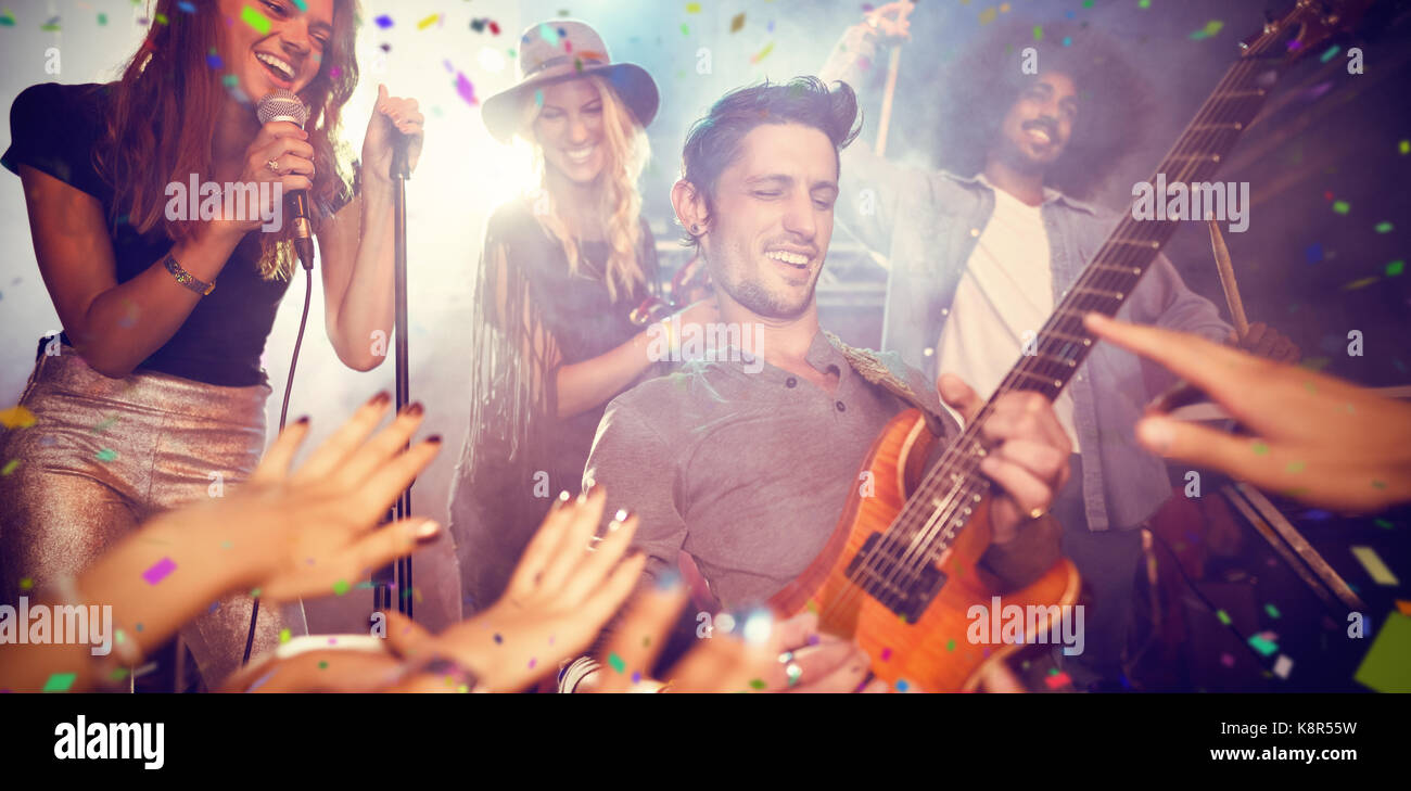 Flying colours against guitarist performing by crowd at nightclub Stock ...