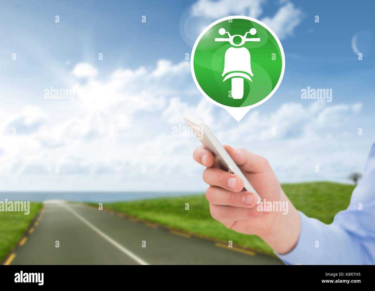 Digital composite of Hand holding phone with motorbike icon on road ...