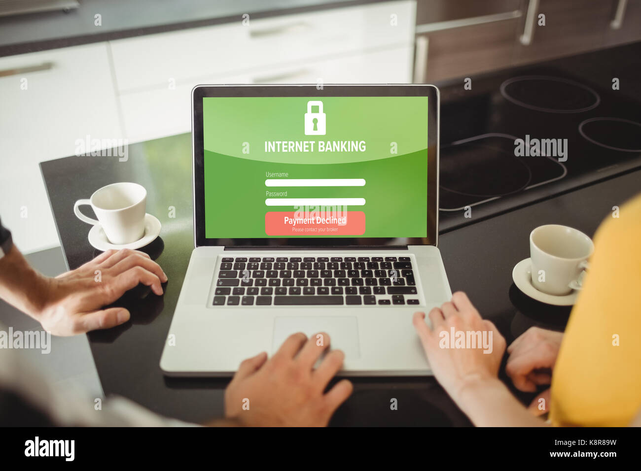 Internet banking text on log in display against couple using laptop in kitchen Stock Photo