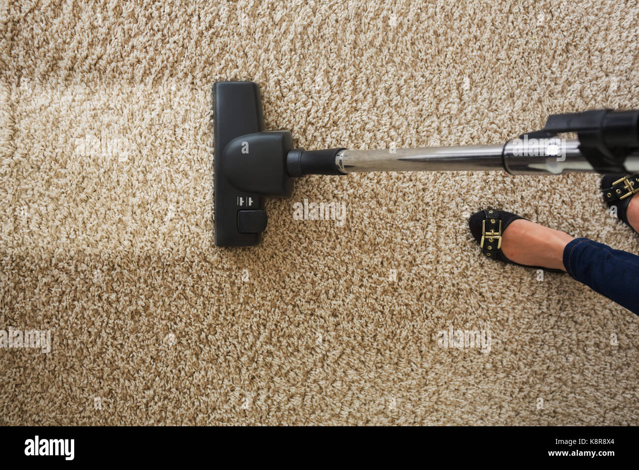 Cropped image of woman cleaning carpet with vacuum cleaner at home Stock Photo