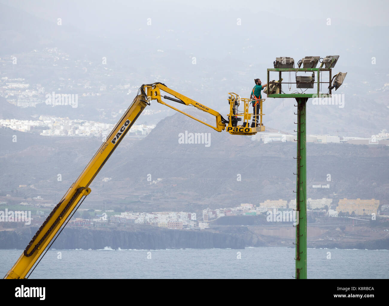 Worker checking football ground floodlights from cherry picker in Spain Stock Photo