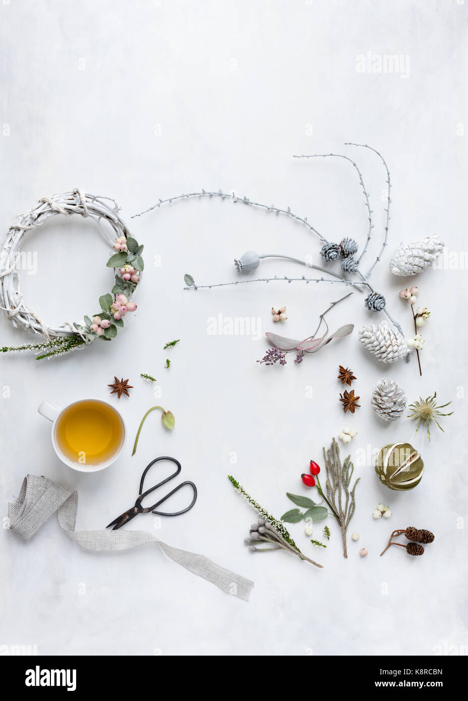 Christmas flatlay with nature gatherings, berries, flowers, wreath, teacup and scissors, spices and dried lime. Natural light, view from above Stock Photo