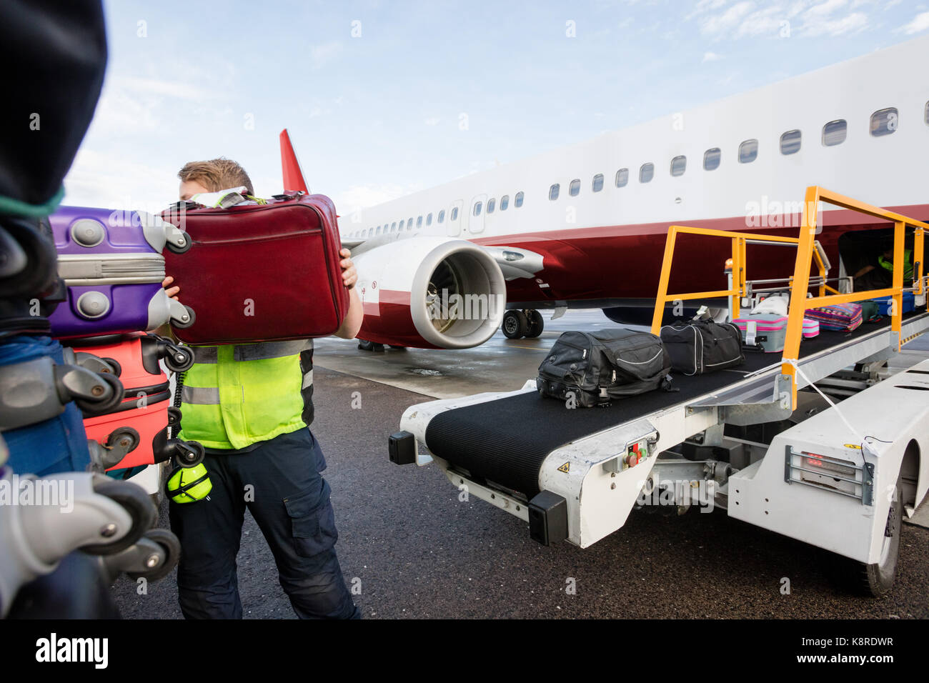 Ground Member Stacking Bags On Trailer At Runway Stock Photo