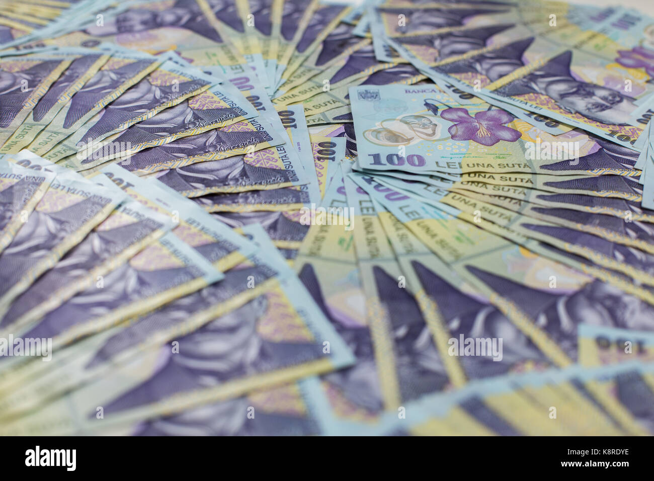 Surface covered with multiple romanian banknotes as a background composition with the shallow depth of field. Romanian banknotes 100 RON. Stock Photo
