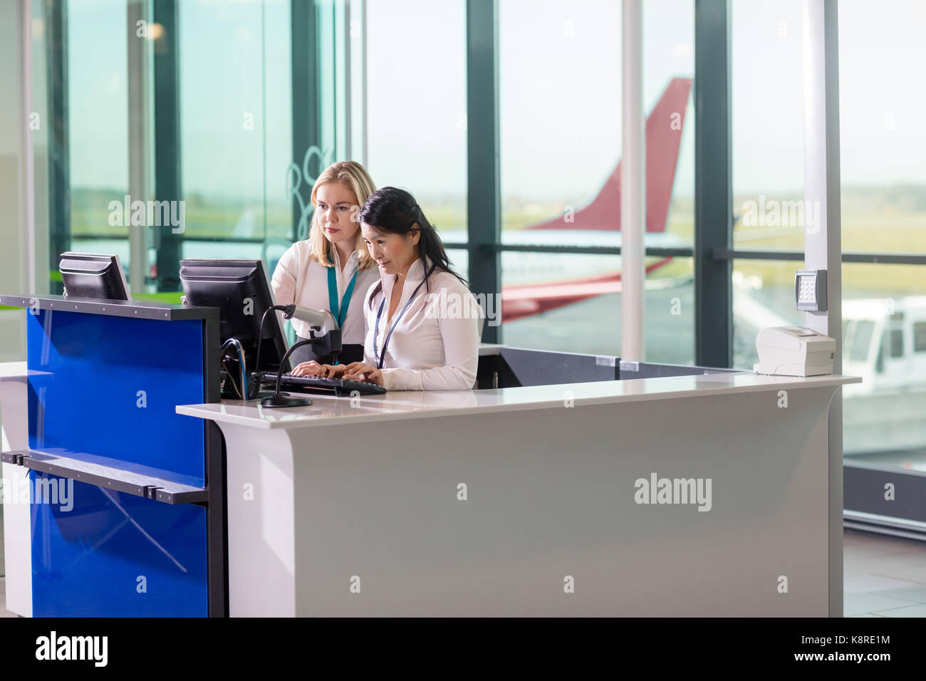 Ground Staff Using Computer At Counter In Airport Stock Photo