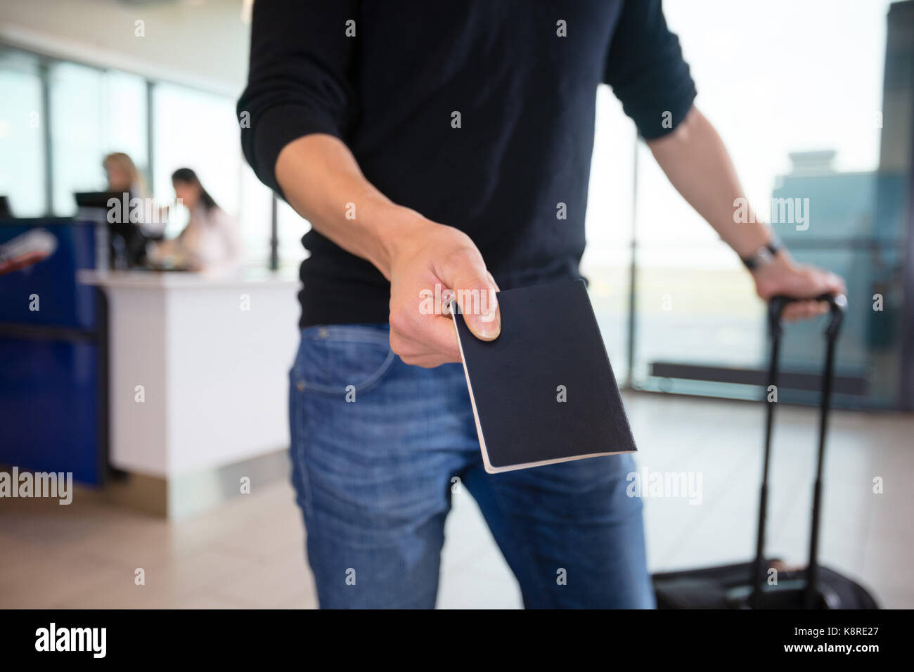 Midsection Of Male Passenger Showing Passport At Airport Stock Photo