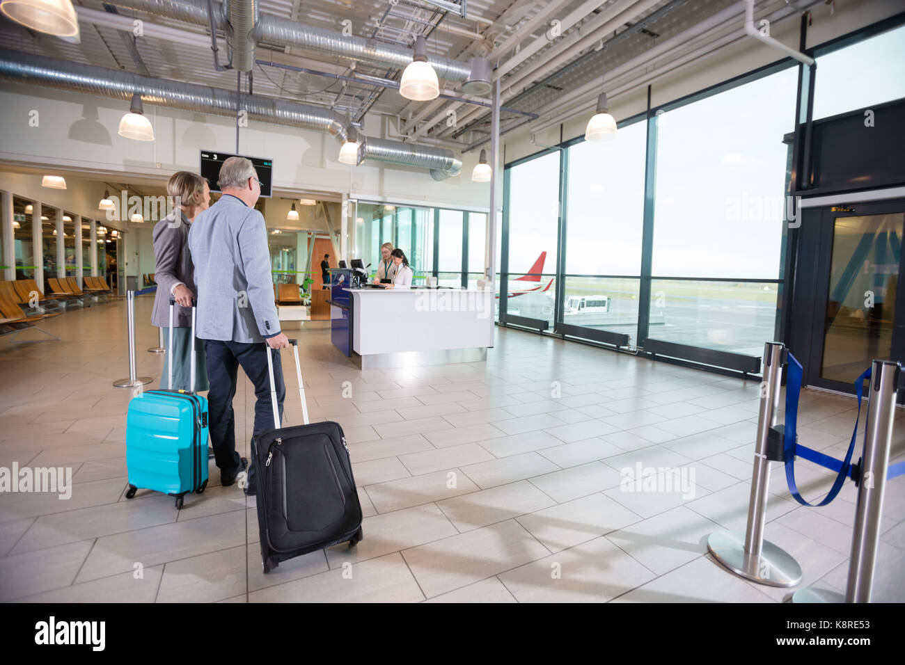 Business Couple Walking Towards Reception In Airport Stock Photo