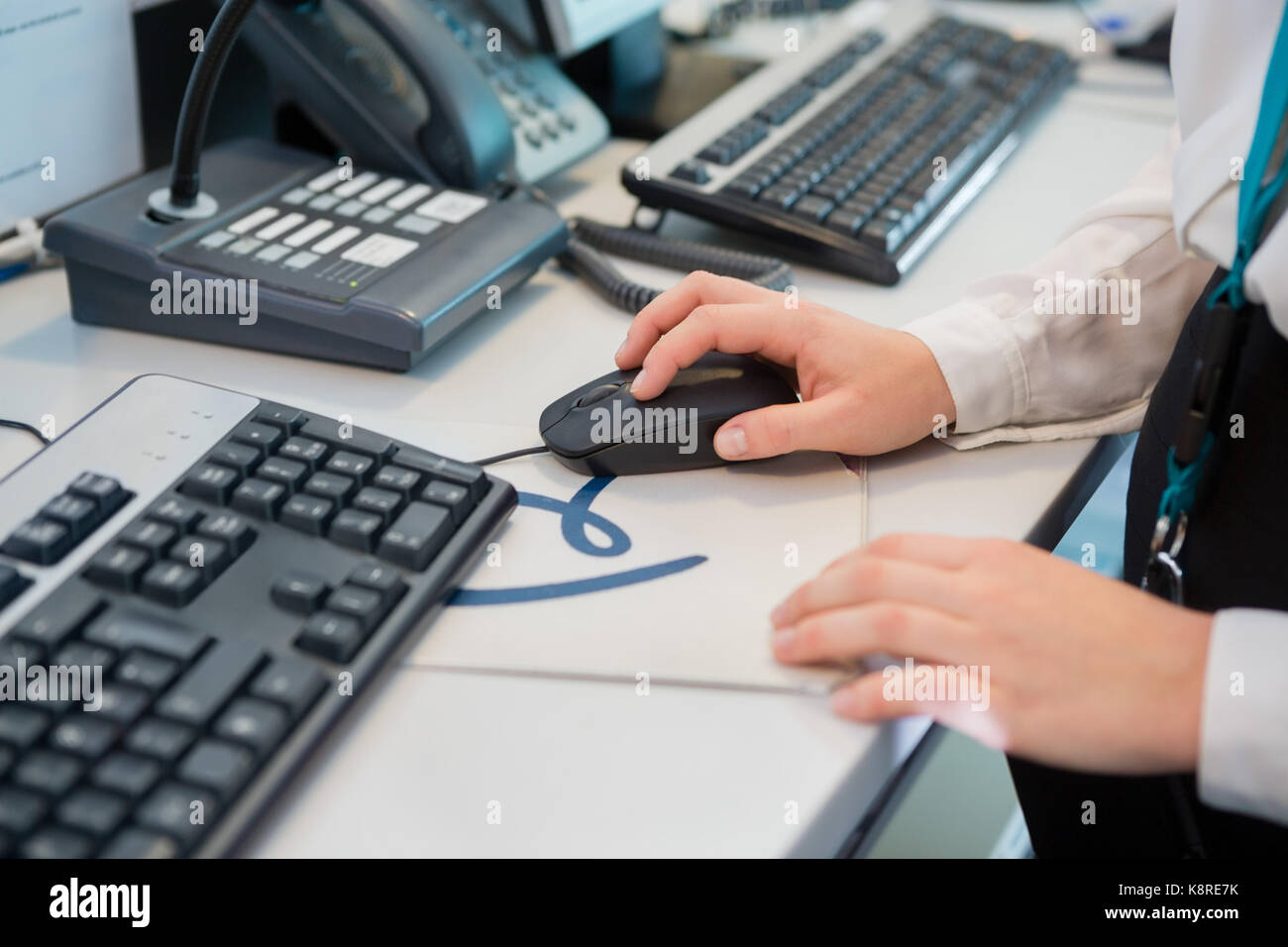 Receptionists Hand Using Computer Mouse At Desk In Airport Stock Photo