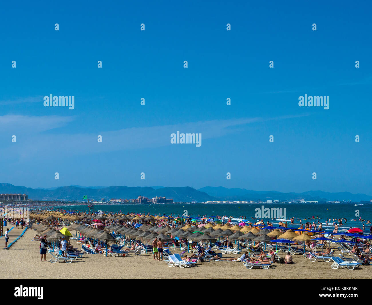 Parasols and sunbathers on Playa del Cabanyal (Las Arenas beach) in summer, Valencia, Spain Stock Photo