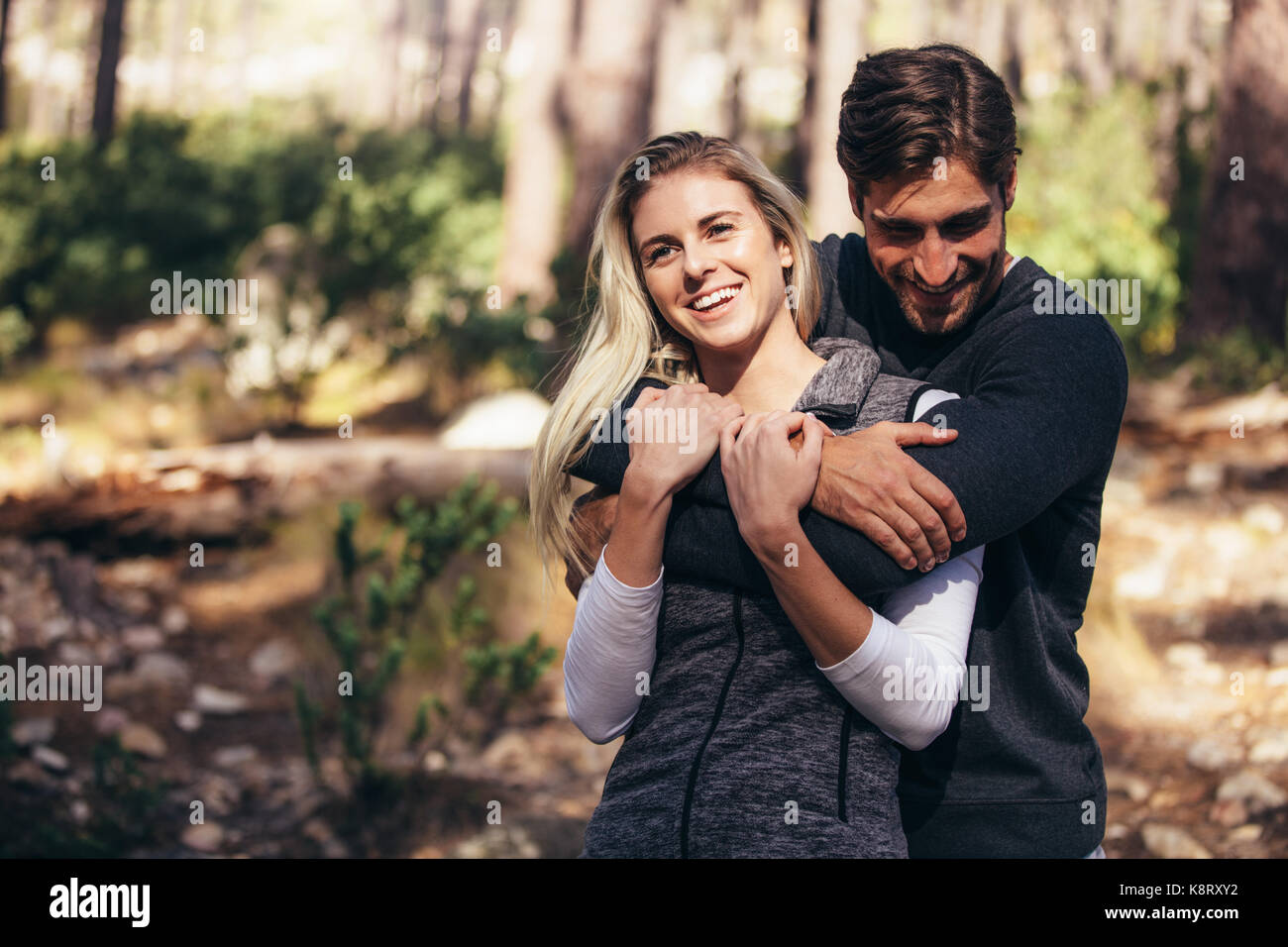 Hiking couple having fun while trekking in forest. Man holding woman ...