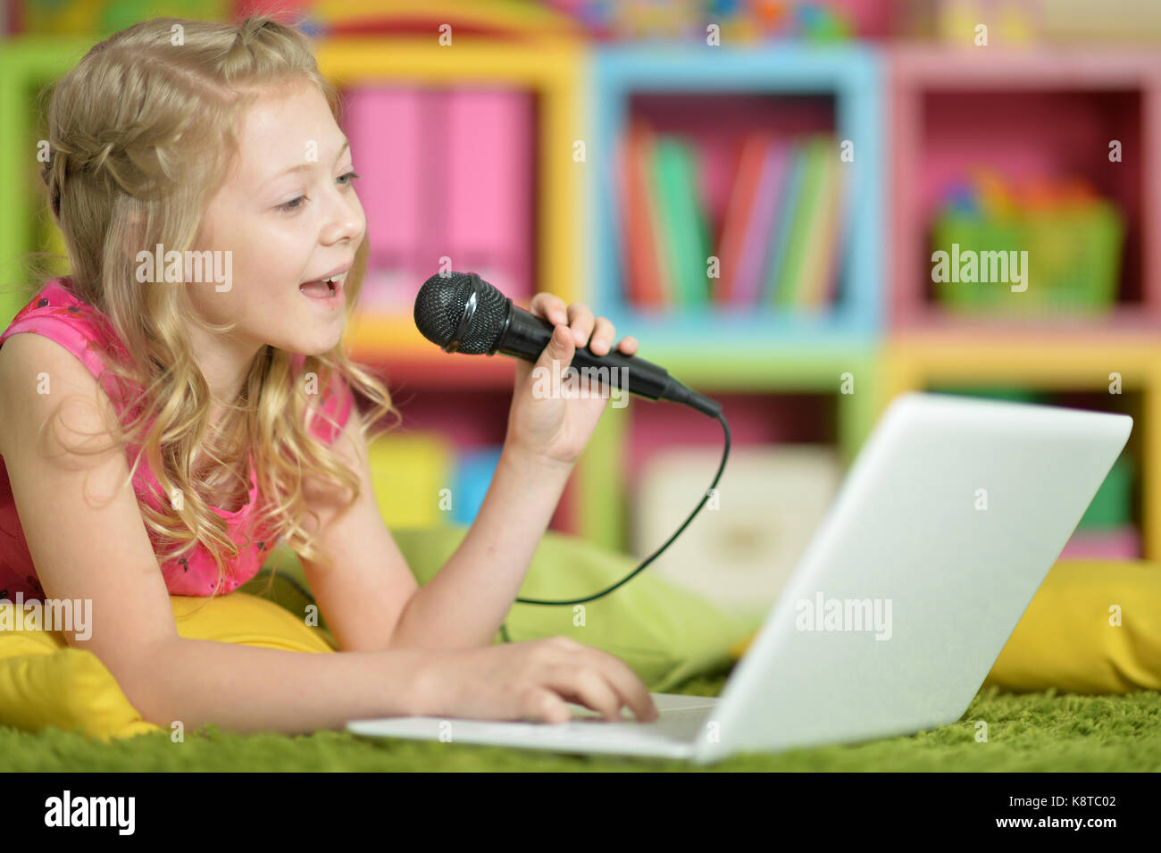 Adorable little girl using modern laptop and singing karaoke Stock