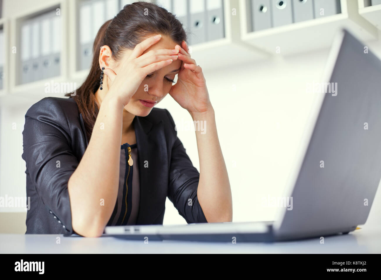 Portrait of tired young business woman with laptop at the office Stock ...