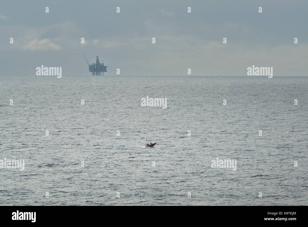 RNLI life boat, rescue craft sailing in the North Sea, with an oil and gas rig in the distance. credit: LEE RAMSDEN / ALAMY Stock Photo