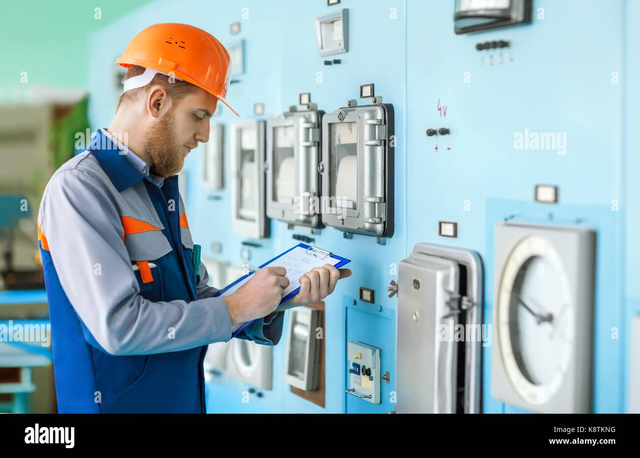 Portrait of young engineer taking notes at control room in factory Stock Photo