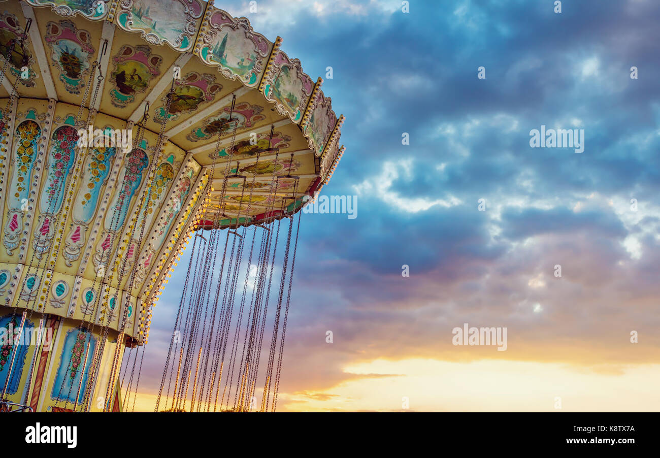 Wave Swinger ride against blue sky, vintage filter effects - no rotating carousel fair ride at dusk Stock Photo