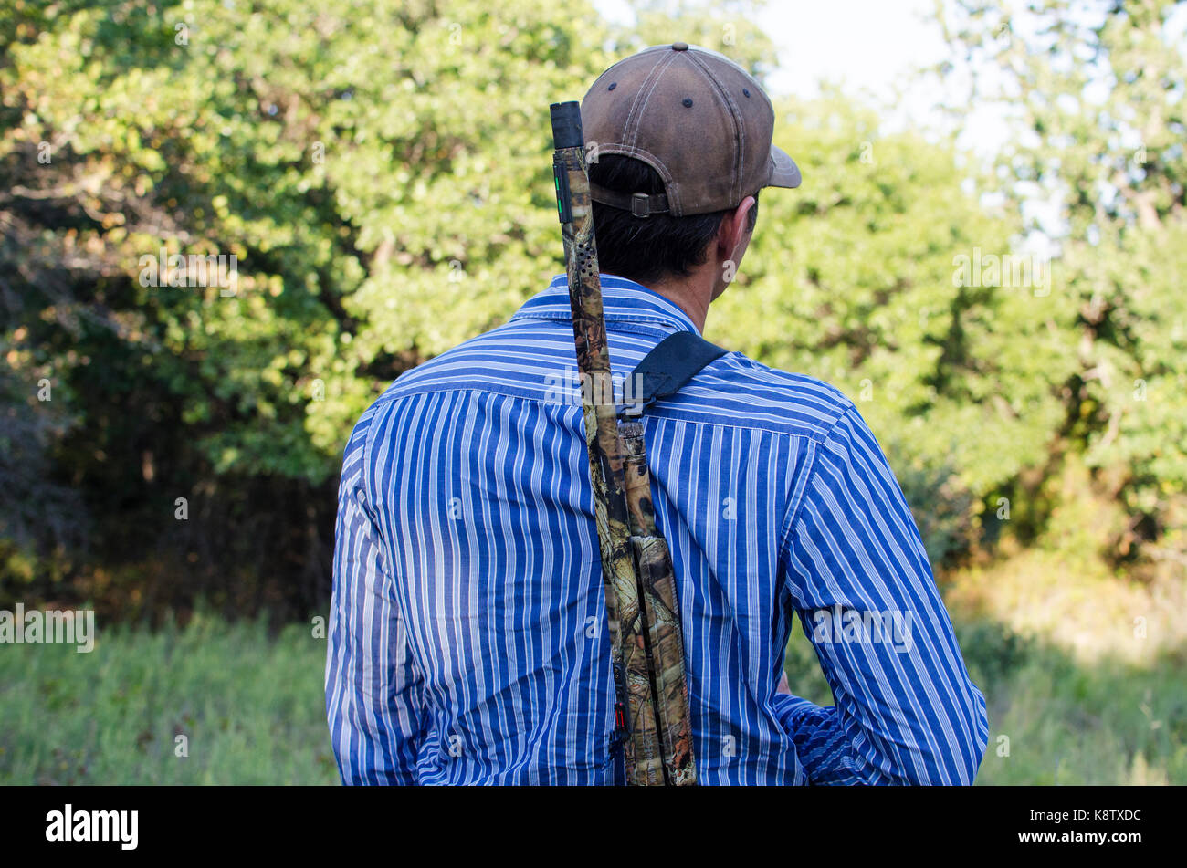 Man walking to woods carrying a shotgun over his shoulder for hunting season. Stock Photo
