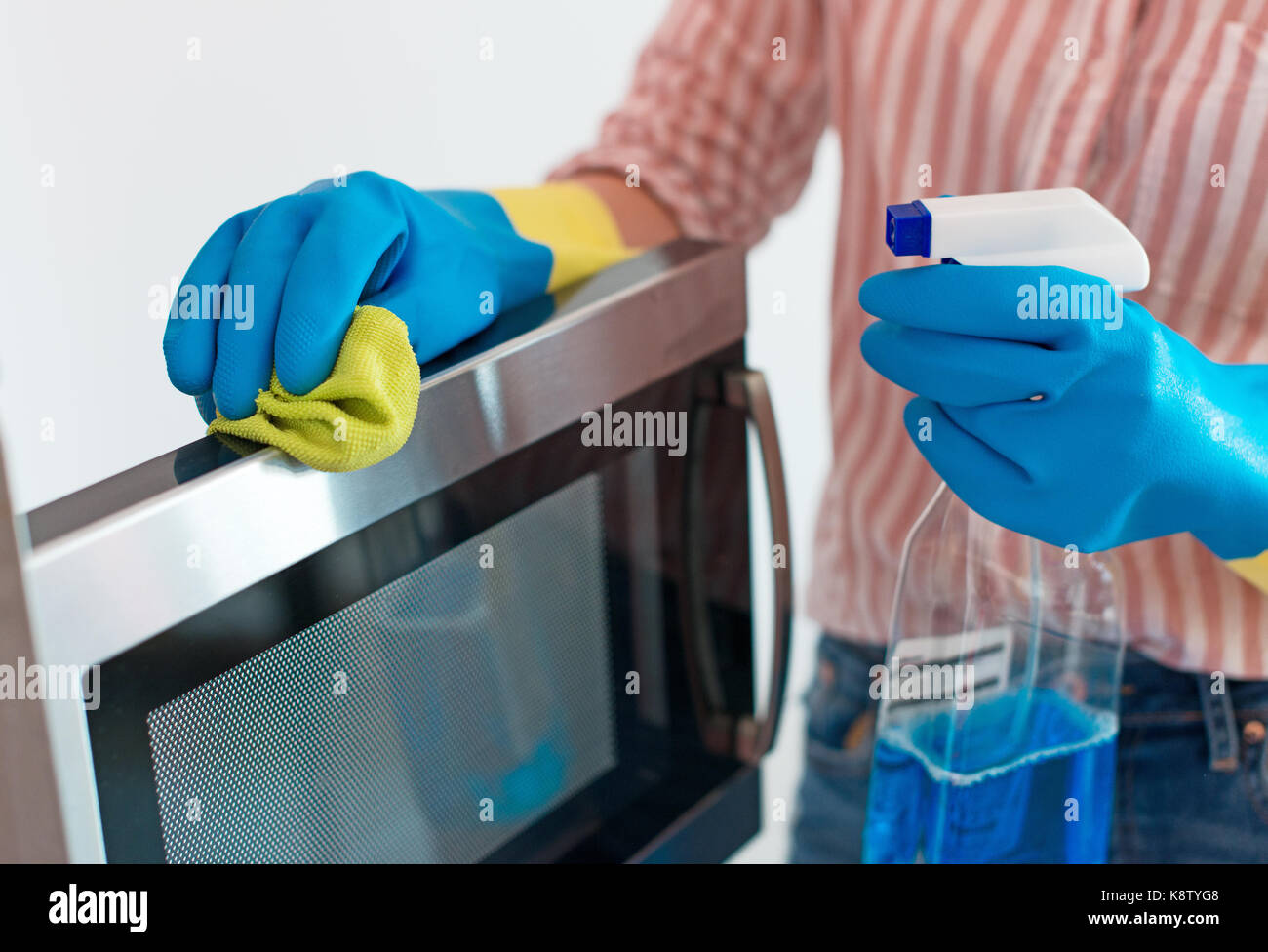 House cleaning. Woman is wiping microwave oven. Stock Photo
