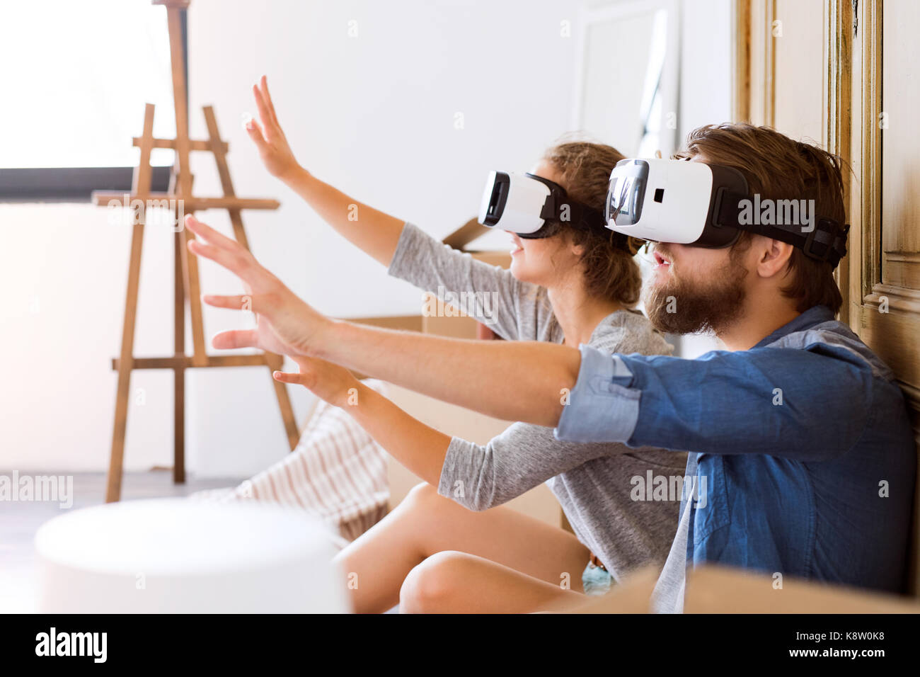 Young couple with VR glasses moving in a new house. Stock Photo