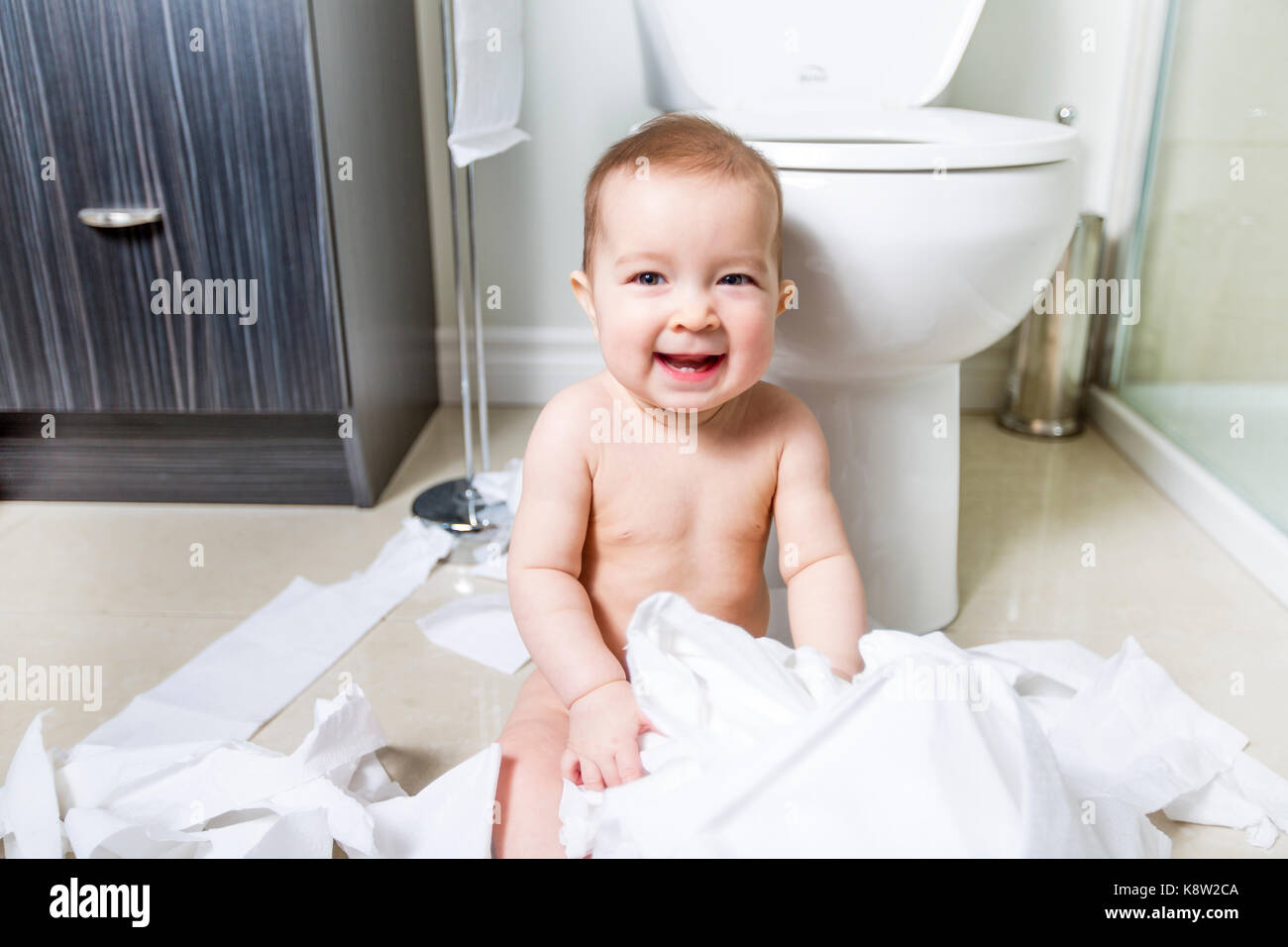 toddler-ripping-up-toilet-paper-in-bathroom-stock-photo-alamy