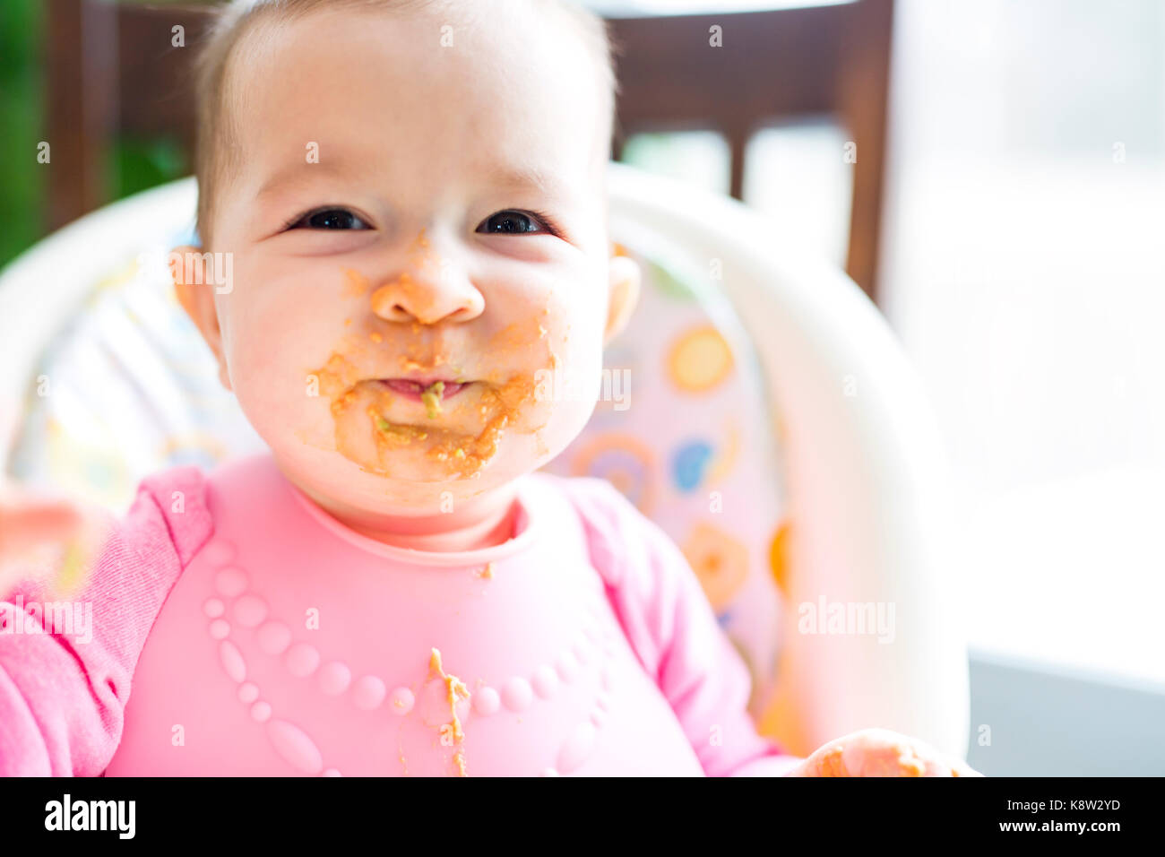 Adorable baby girl making a mess while feeding herself Stock Photo Alamy