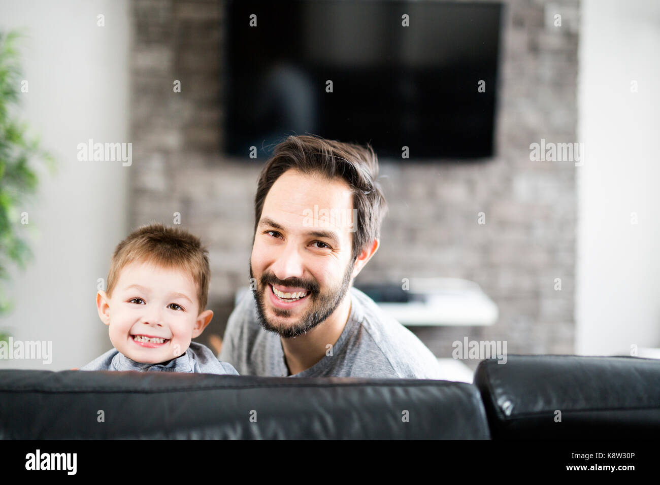 Father And Children On Sofa At Home Watching TV Together Stock Photo