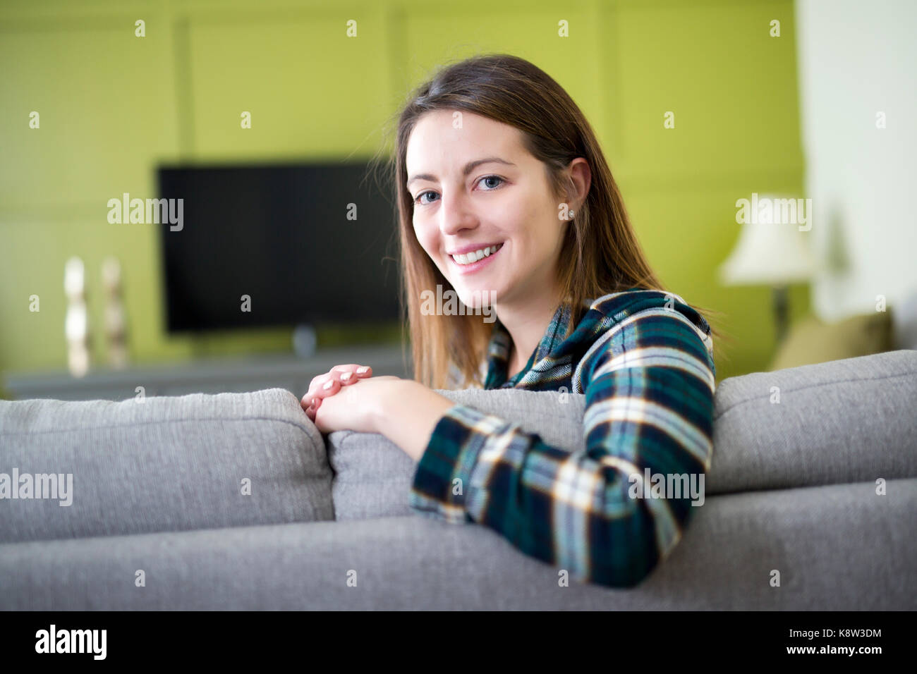 Beautiful woman watching TV sitting on couch at home Stock Photo