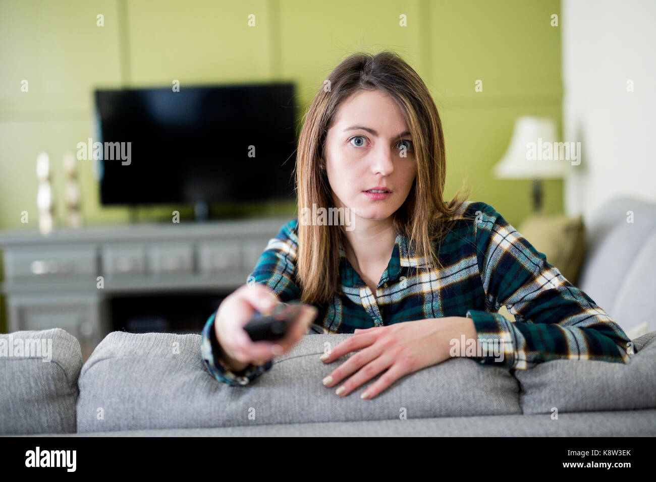 Beautiful woman watching TV sitting on couch at home Stock Photo - Alamy