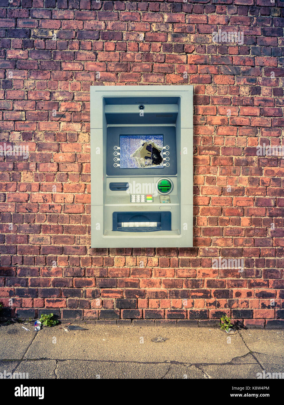 A Vandalized ATM Against A Grungy Red Brick Wall Stock Photo
