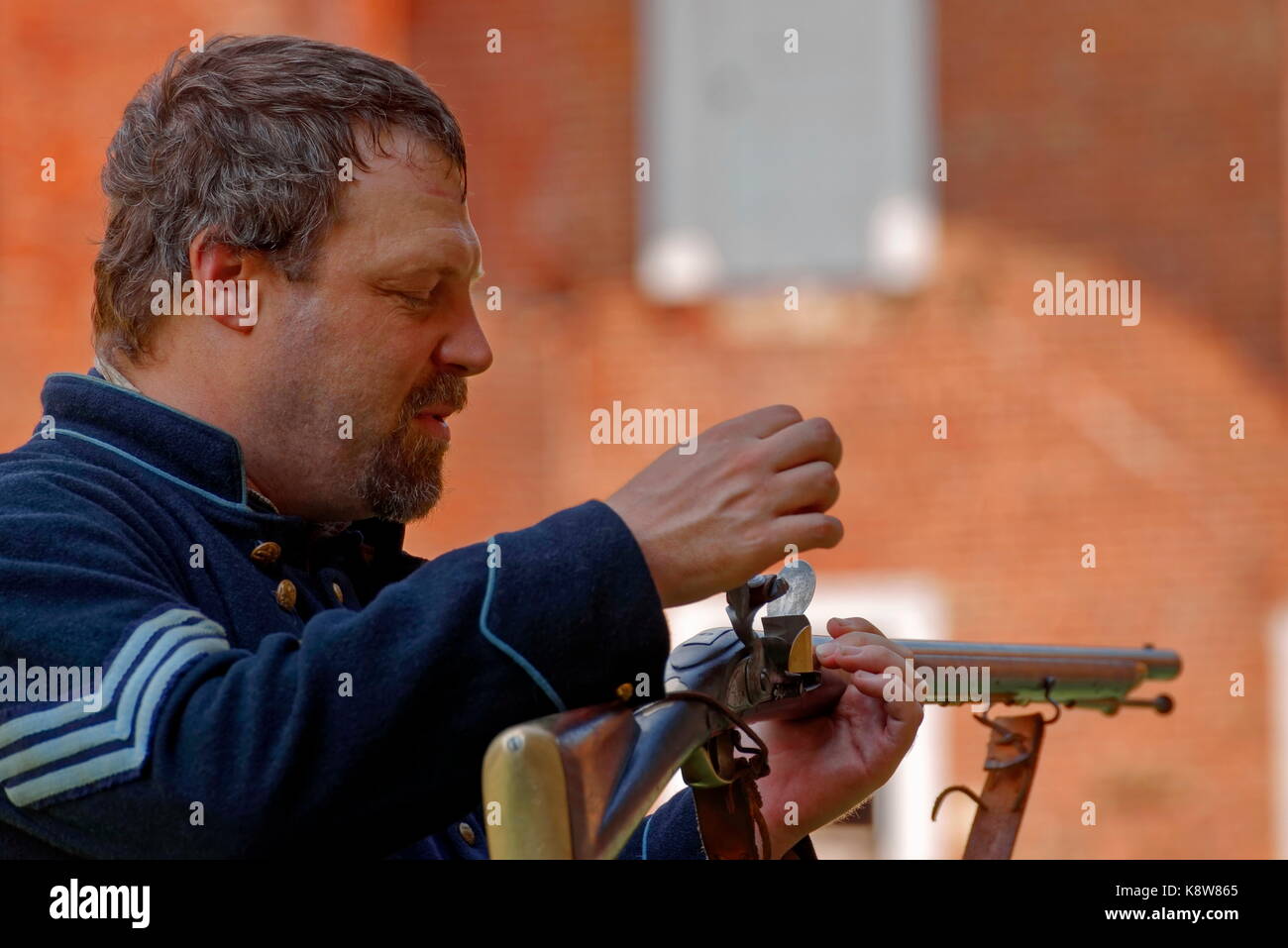 Civil war re-enactor in Union uniform demonstrates a flintlock  muzzle loading musket. Stock Photo