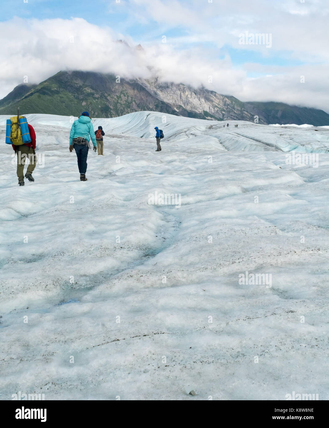 People are hiking up an incline on Root Glacier. Stock Photo