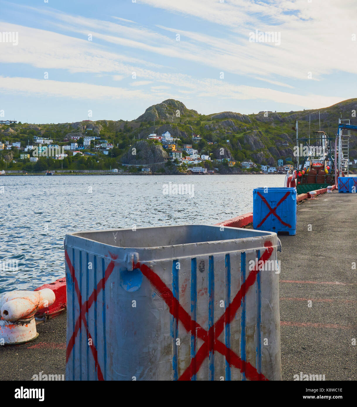 Fish storage boxes on jetty with Signal Hill in the background, St John's, Newfoundland, Canada Stock Photo