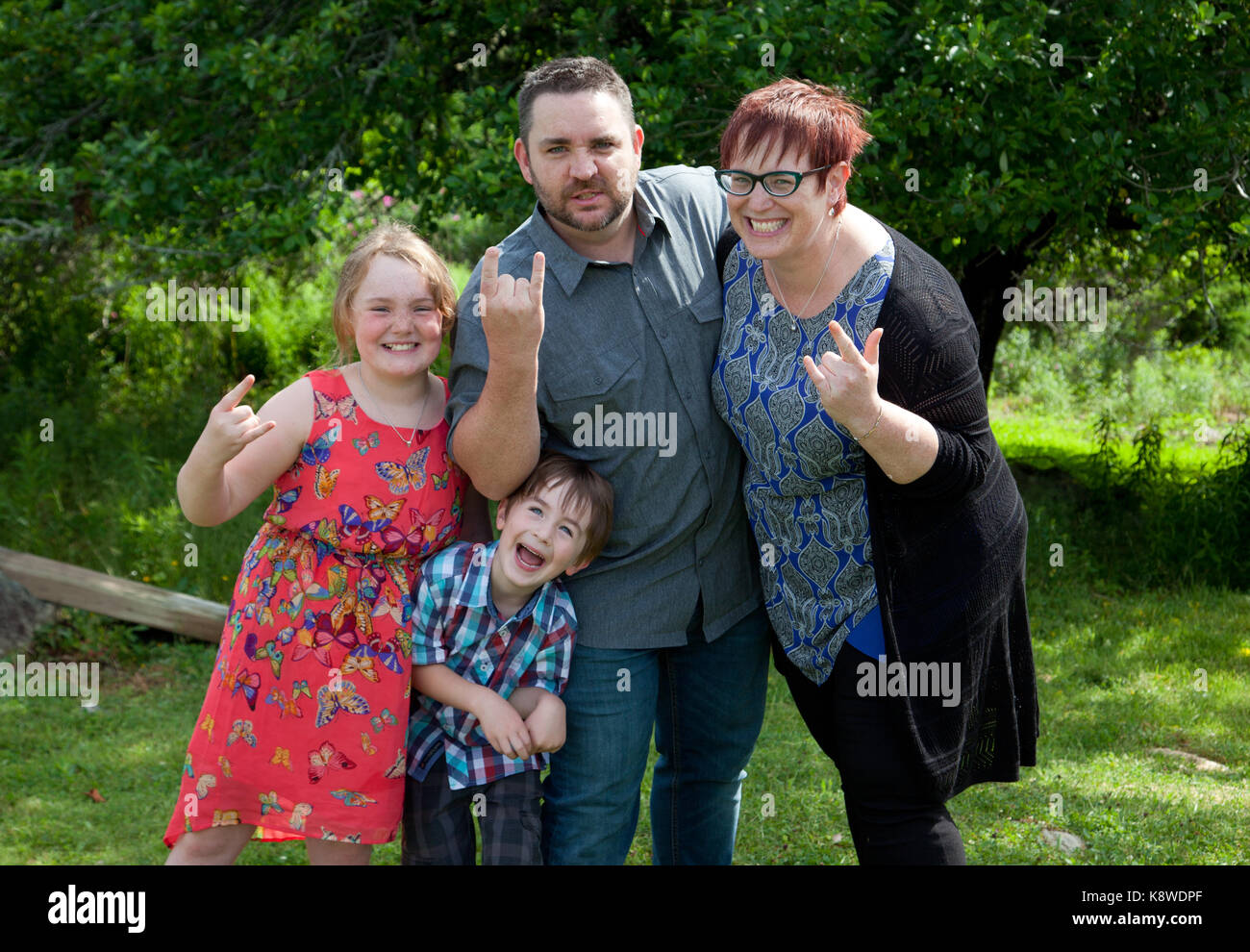a family of four makes silly faces and devil horns outside Stock Photo