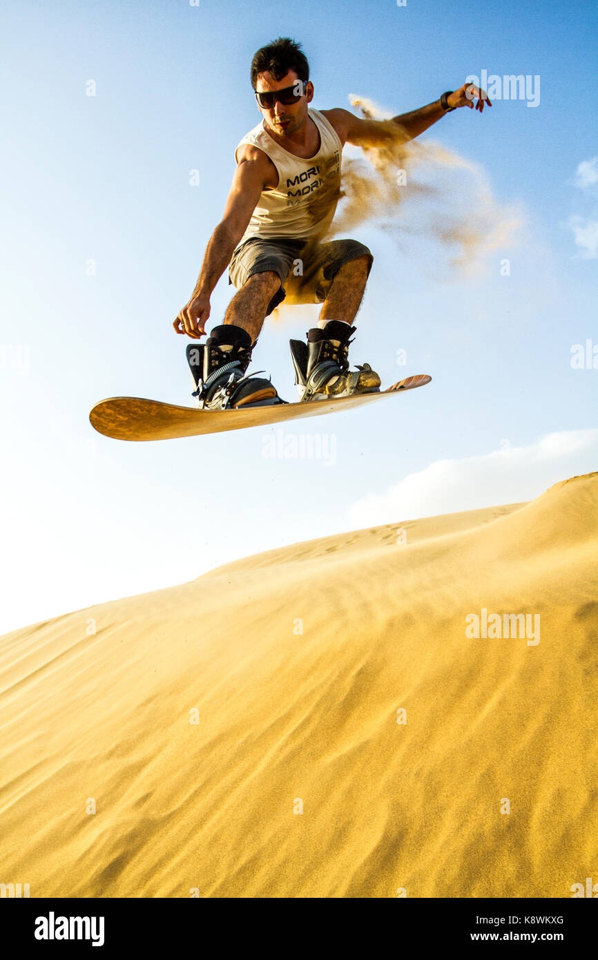 Young man sandboarding on the dunes of Medanos de Coro National Park. Coro, Falcon State, Venezuela. Stock Photo