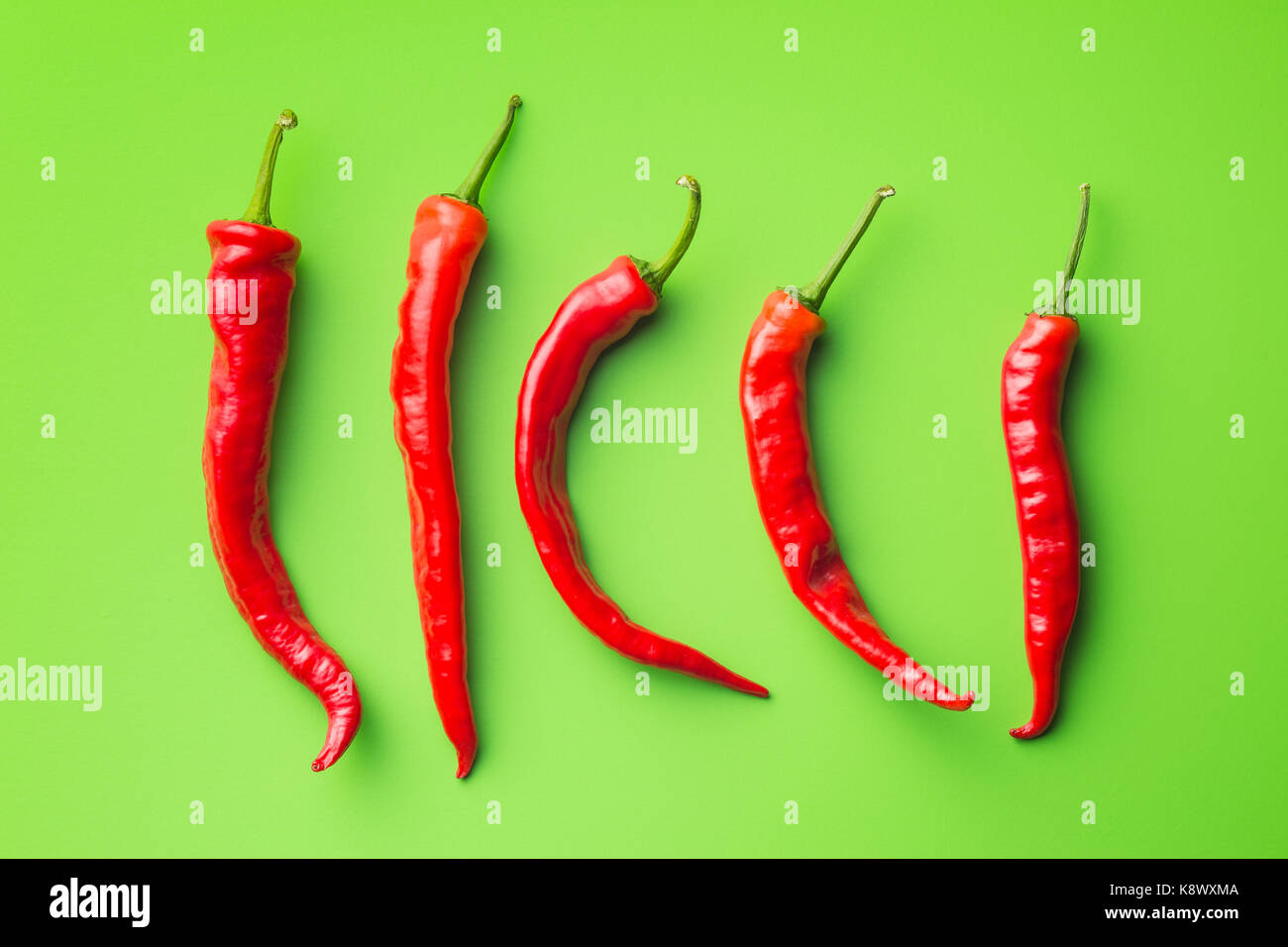 Red chili peppers on green background. Top view Stock Photo - Alamy