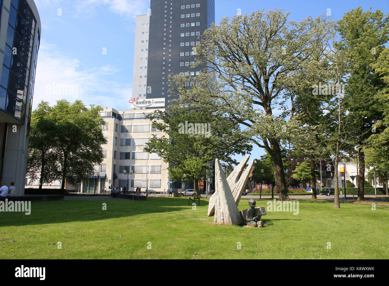 Small park with sculpture of playing boy.  IN background 115m high Achmeatoren (Achmea tower offices.) Highest building in Leeuwarden, Netherlands. Stock Photo