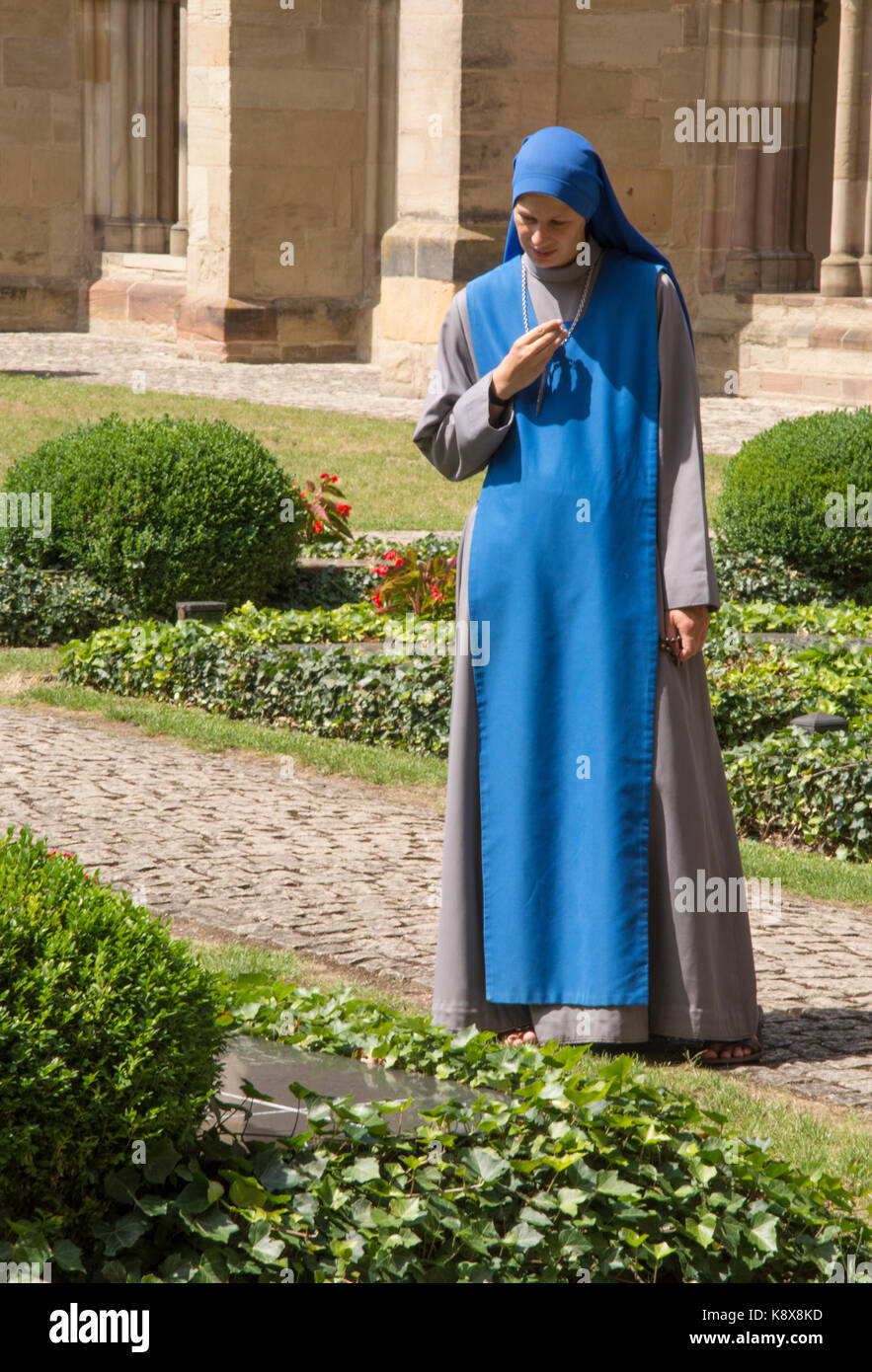 A young nun (or novitiate) in contemplative mood, strolling in the cathedral cloister, Trier, Germany Stock Photo