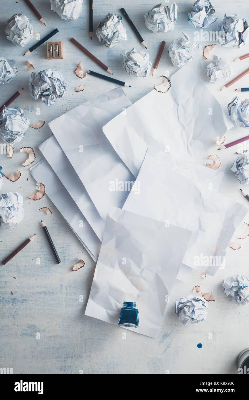Blank paper on a wooden background with inkwell and scattered crumpled