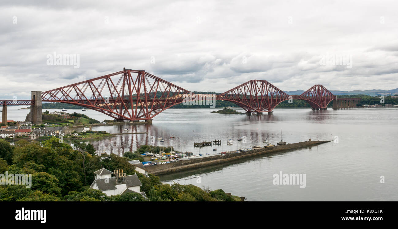 View of cantilever Forth Rail Bridge and North Queensferry village with calm water in Firth of Forth Stock Photo