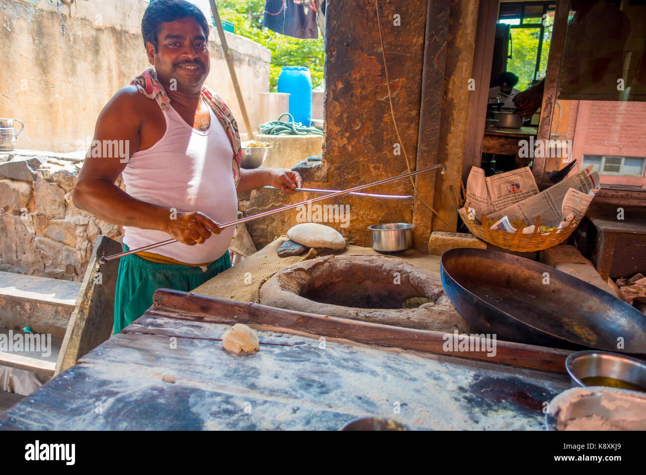 Jaipur, India - September 20, 2017: Unidentified man cooking in the kitchen homemade small tortillas inside of a stone oven, for breakfast in Jaipur city, in India Stock Photo