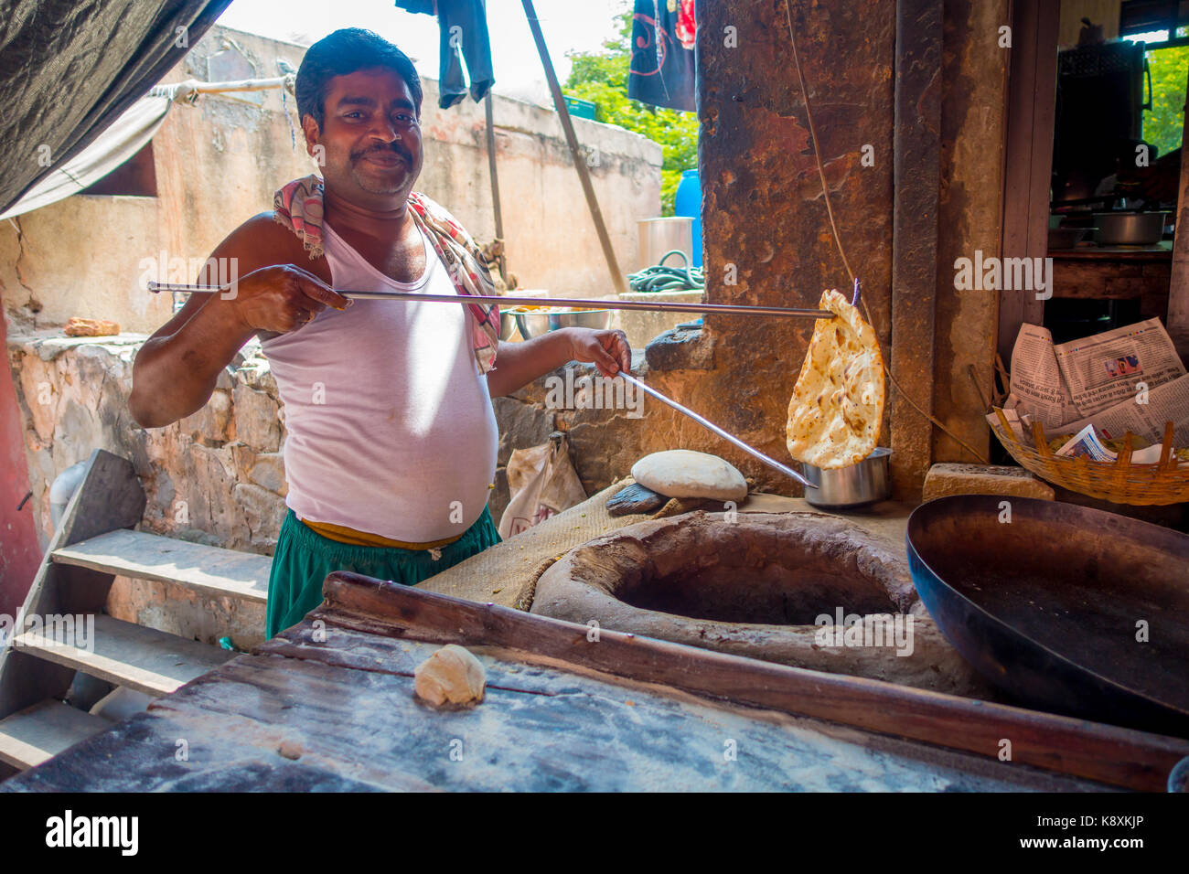 Jaipur, India - September 20, 2017: Unidentified man cooking in the kitchen homemade small tortillas inside of a stone oven, for breakfast in Jaipur city, in India Stock Photo